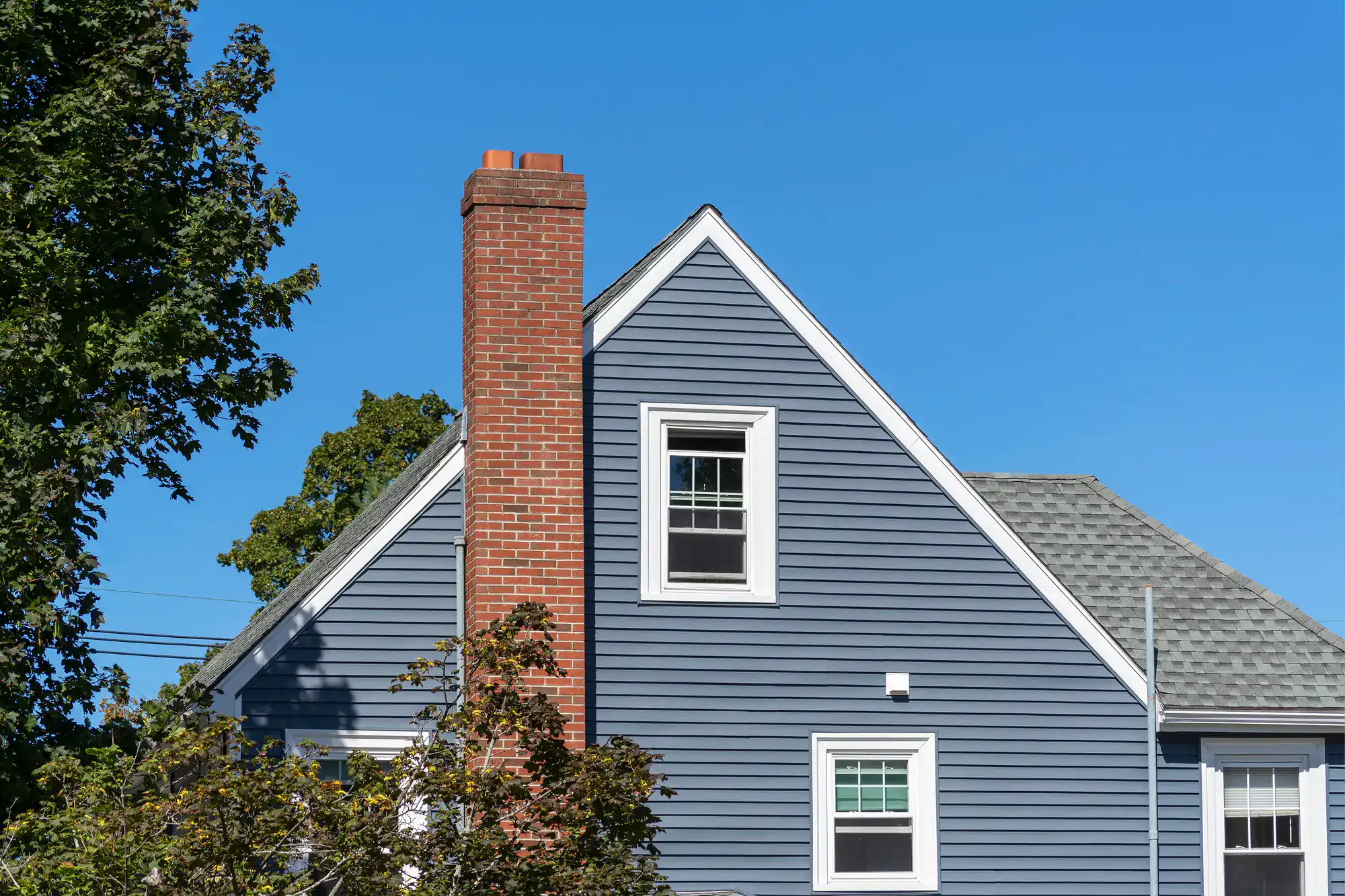 Blue house with a prominent gable side featuring brick masonry work, showcasing Academy Masonry’s craftsmanship on the exterior walls.
