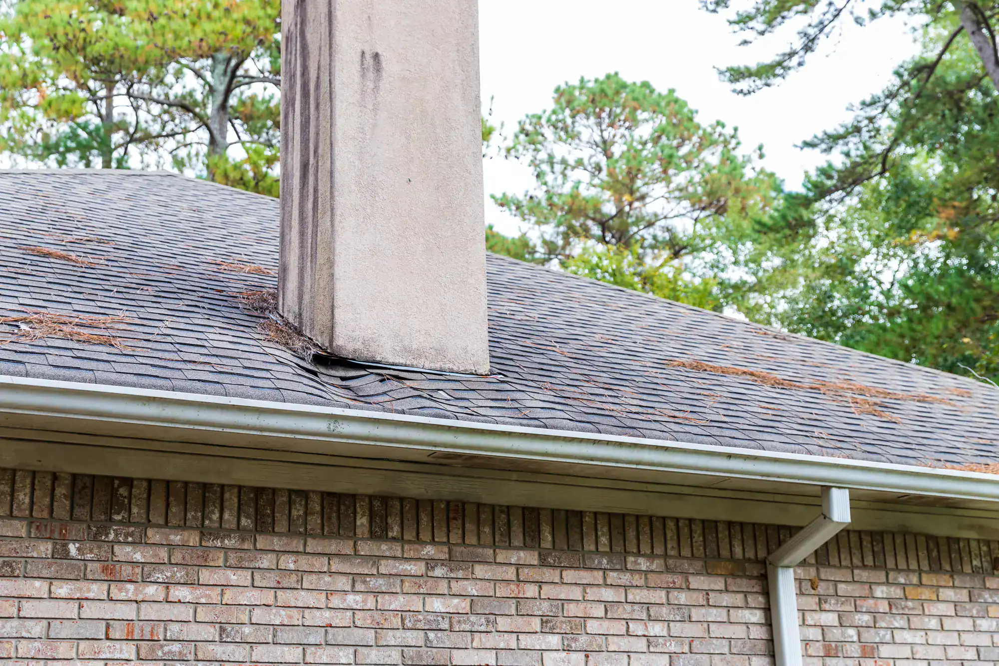 Close-up view of a damaged roof chimney showing cracked bricks and missing mortar, highlighting areas in need of repair, for Academy Masonry.