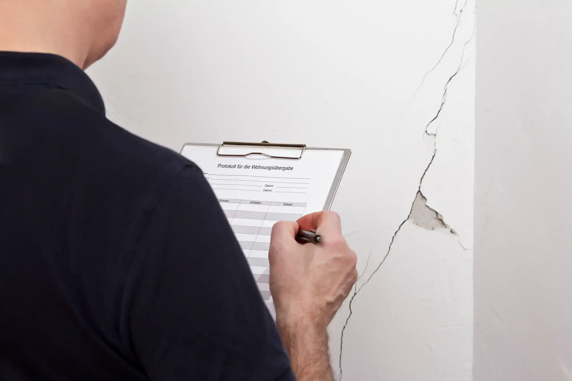 A professional mason from Academy Masonry carefully inspecting a vertical wall crack on a residential building in Suffolk County, Massachusetts, examining structural integrity with attention to detail.