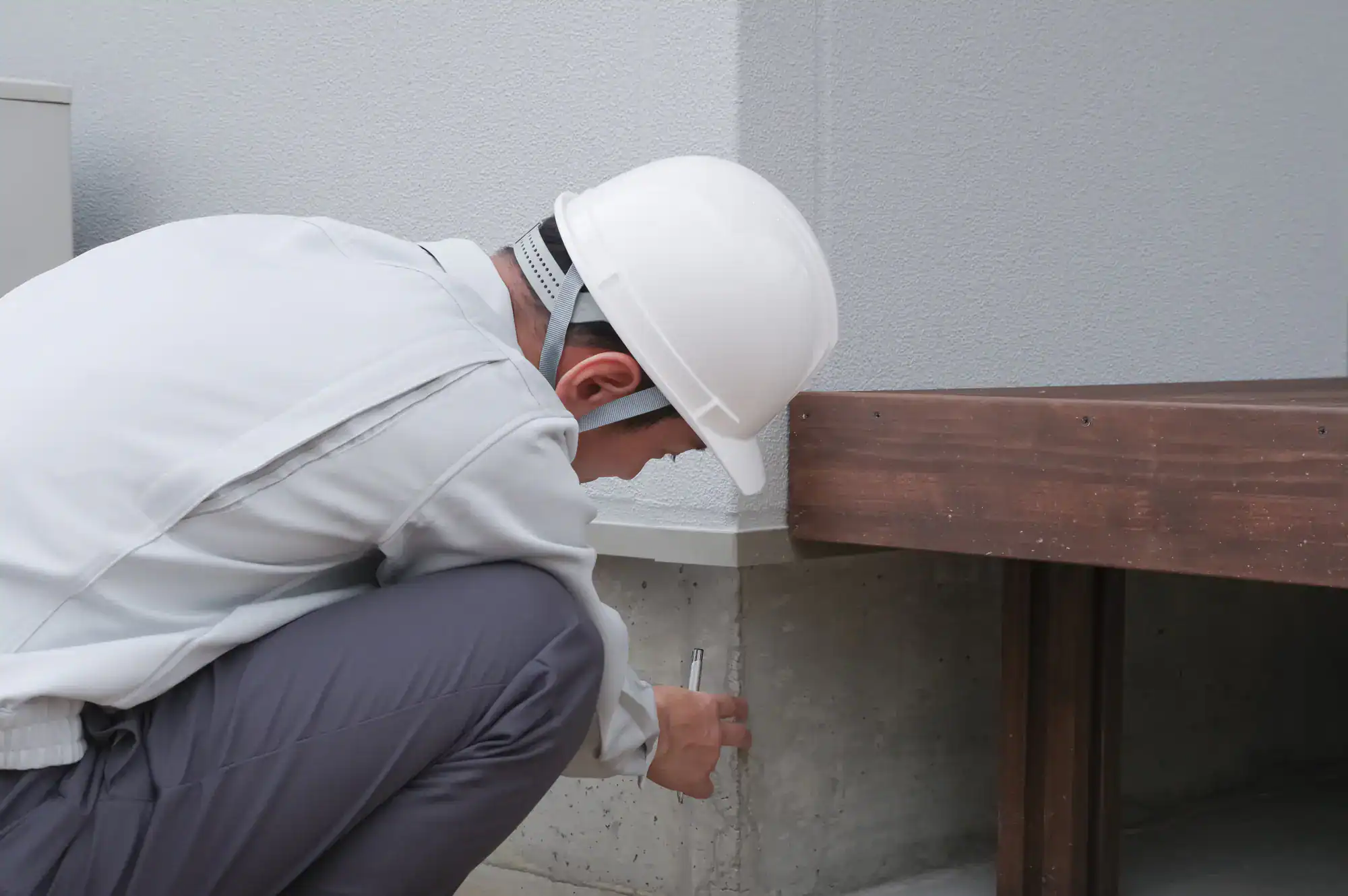 Inspector examining the foundation of a residential property in Suffolk County, Massachusetts, ensuring structural integrity, with Academy Masonry logo visible on site.