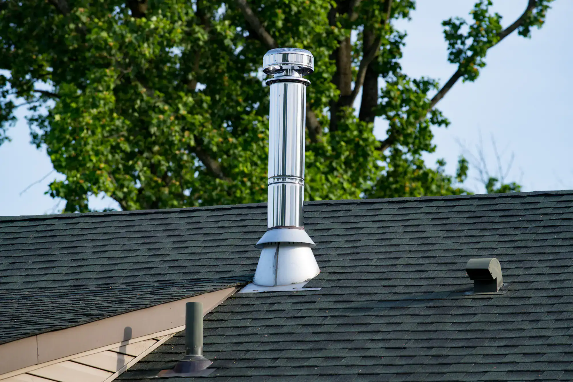 Rooftop view showing a newly installed chimney pipe with clean masonry work, professionally completed by Academy Masonry.