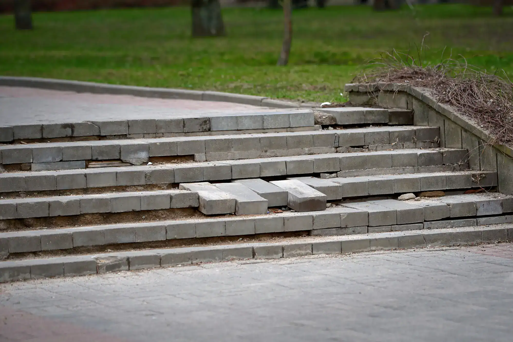 Uneven, weathered stone stairs with cracks and broken edges, showing signs of wear and age, installed by Academy Masonry. Each step has a rough texture, irregular shapes, and natural stone colors, illustrating the challenges of maintaining old masonry stairs.
